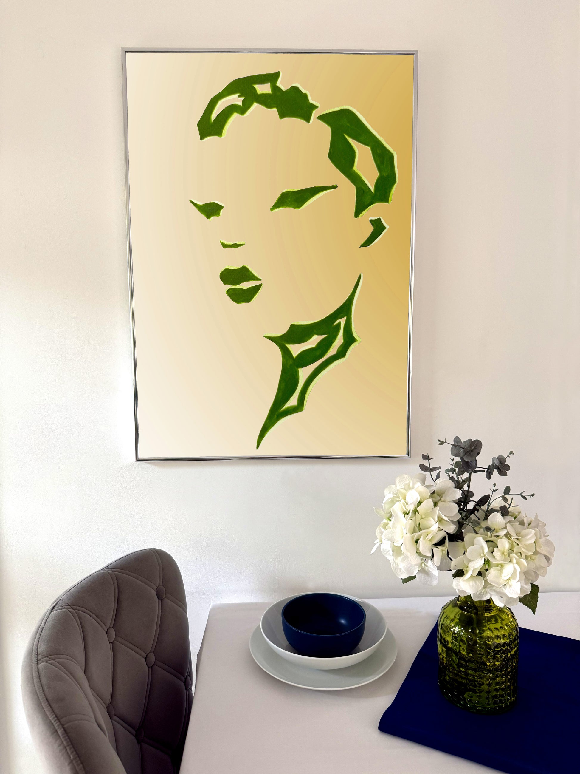 Framed green silhouette art on a wall above a table with decorative items.